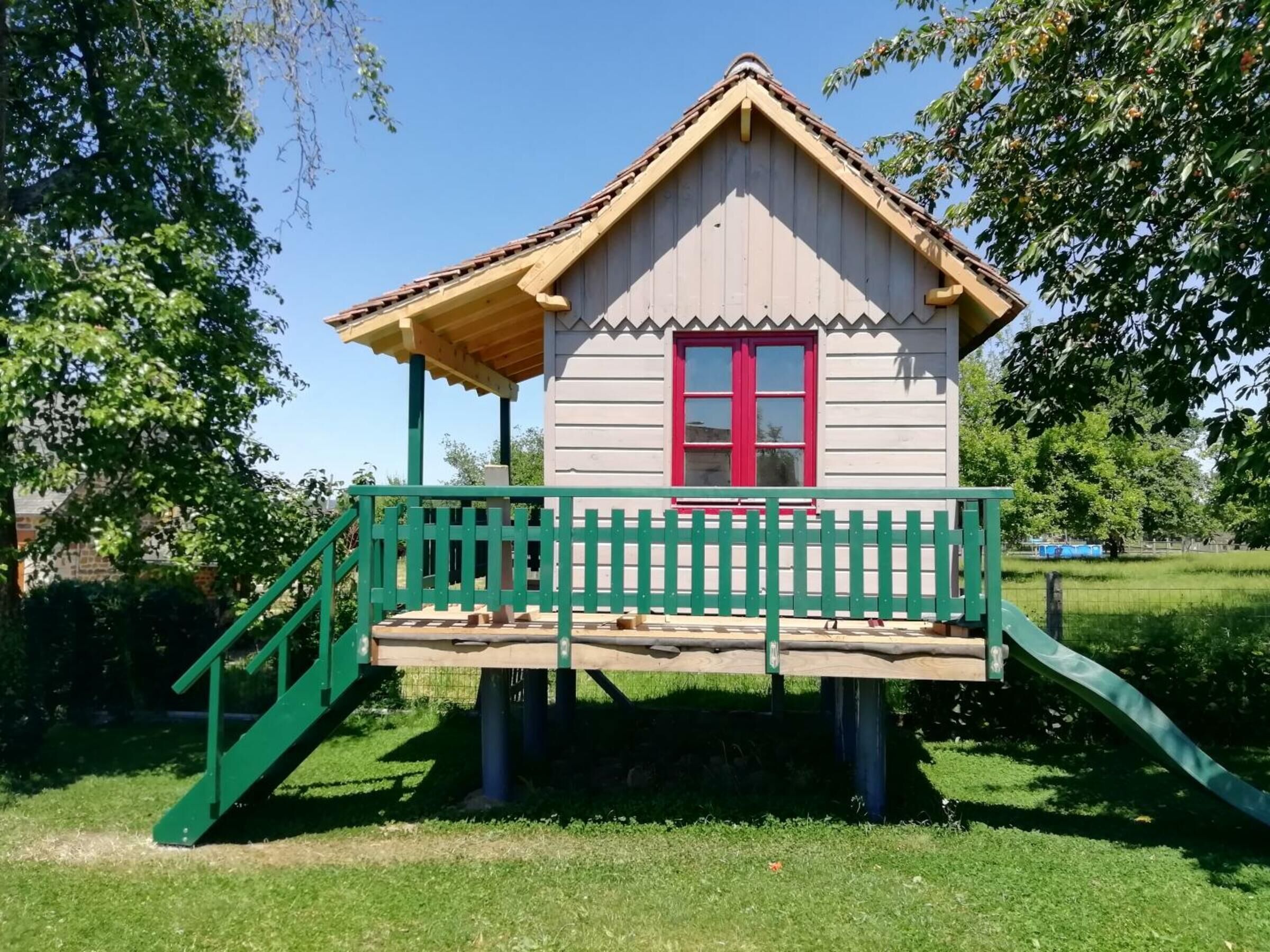 A small wooden house with a red door and a green porch.