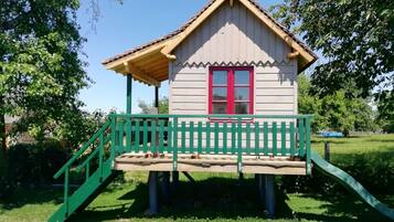 A small wooden house with a red door and a green porch.