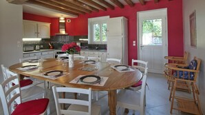 A dining area with a wooden table set for four, surrounded by white chairs.
