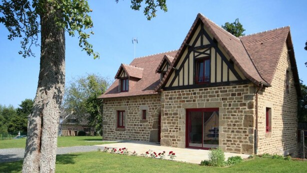 A stone building with a pitched roof, a large window, and a door.