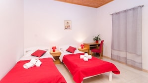 A room with two beds, each with red bedding and white pillows, a desk with a chair, a small table, and a potted plant. - Apartments Grga - Studio Apartment with Balcony and City View (Dubrovnik)