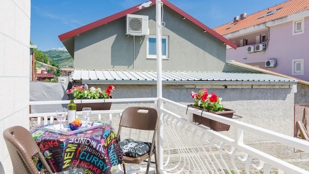 A balcony with a table set for dining, a chair, and potted plants. - Apartments Grga - Studio Apartment with Balcony and City View (Dubrovnik)