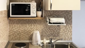 A compact kitchen with a microwave, kettle, stove, and sink. - Nika Family Apartments - Basic Studio Apartment with External Terrace and Sea View (A5) (Dubrovnik)
