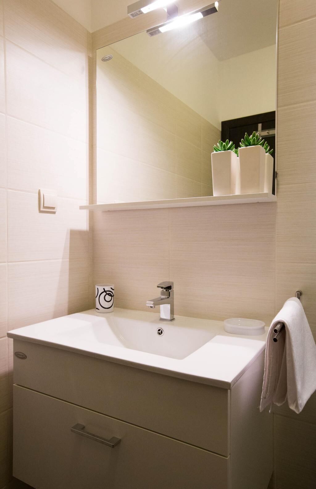 A modern bathroom with a white sink, a mirror, and a towel rack.