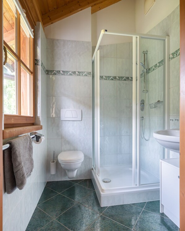 A bathroom with a toilet, a shower with a glass door, and a sink.