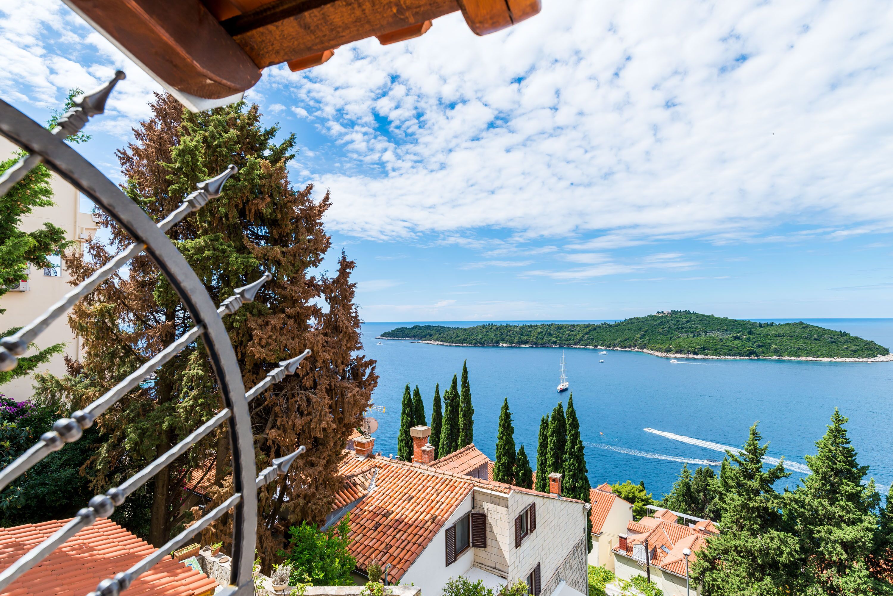 A coastal view with a clear sky, a boat on the water, and a mountainous island in the distance.