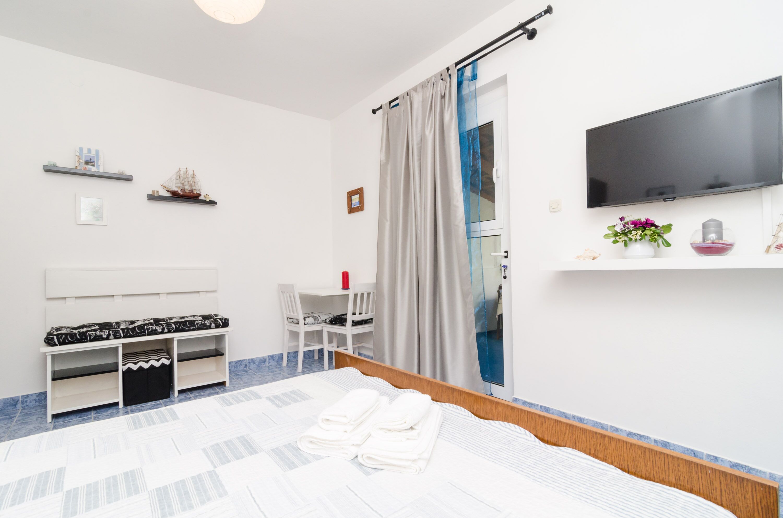 Une chambre d’hôtel équipée d’un lit, d’un bureau, d’une chaise, d’une télévision et d’une fenêtre avec des rideaux.