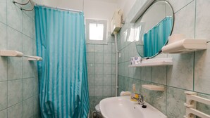 A bathroom with a shower curtain, a sink, a mirror, and a window.