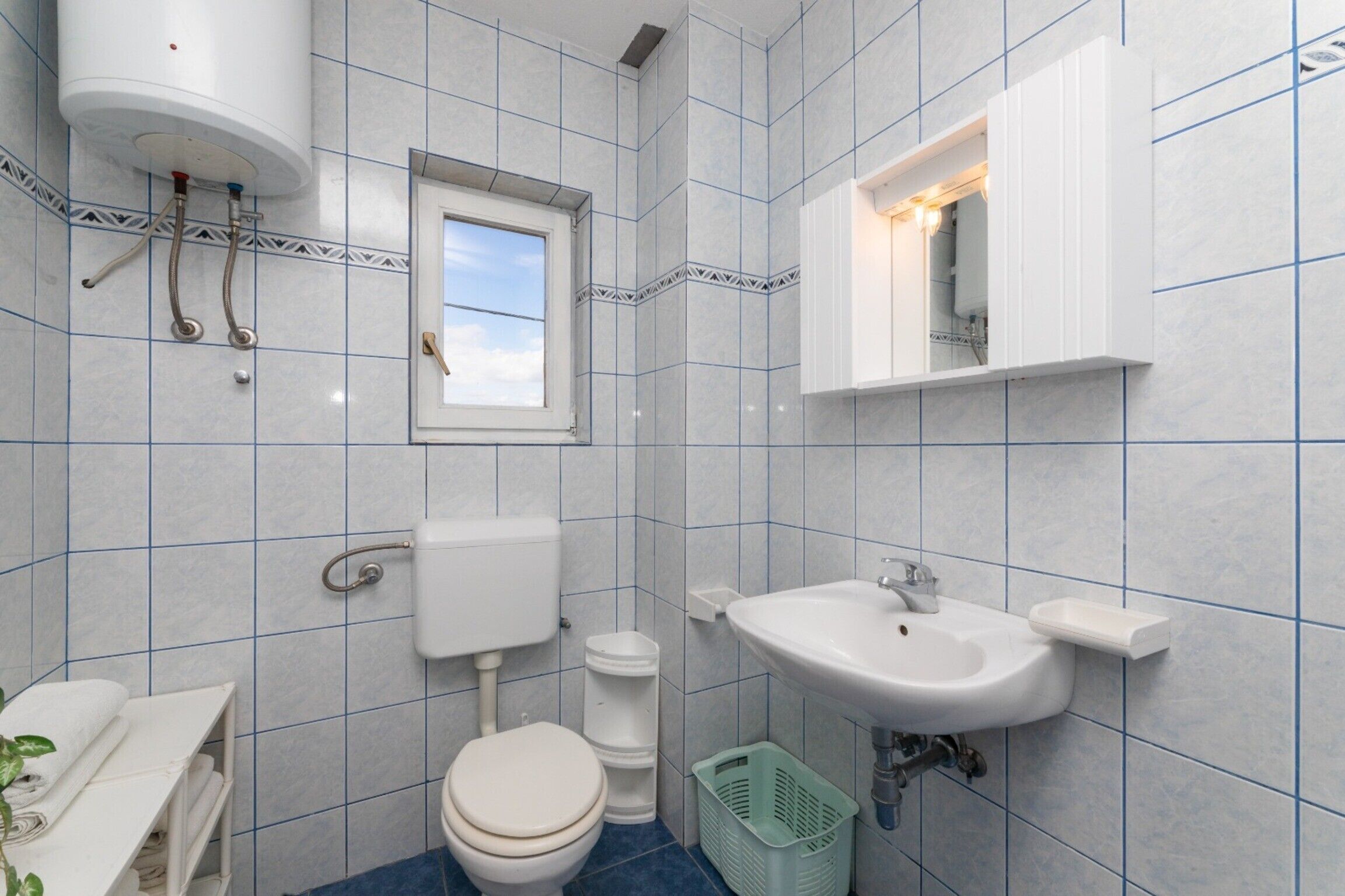 Een badkamer met toilet, wastafel en raam.