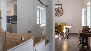 Uma cozinha moderna com divisória de vidro, bancada de madeira e área de refeições com mesa e cadeiras.