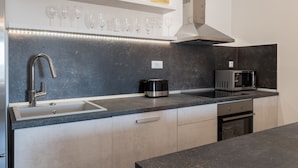 Uma cozinha moderna com uma pia de aço inoxidável, cafeteira, micro-ondas e forno embutido.