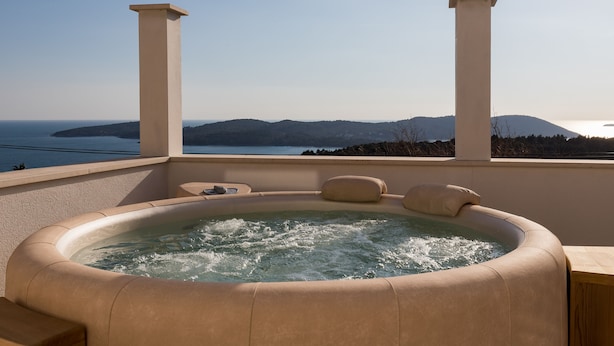 Uma banheira de hidromassagem com vista para o mar e montanhas.