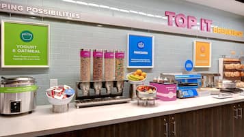 A breakfast station with yogurt, oatmeal, pancakes, eggs, and a variety of toppings.