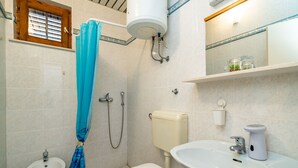 Un baño con inodoro, bidé, lavamanos y ducha.