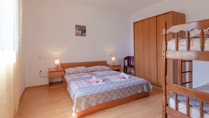A bedroom with a wooden bunk bed, a bedside table with a lamp, a small cabinet, and a single bed with a patterned bedspread. - Seafront Apartments Olivera-One Bedroom Apartment with Balcony and Sea View ( Ante ) (Vela Luka)