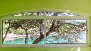A room with a large window overlooking a turquoise body of water and trees. - Seafront Apartments Olivera-One Bedroom Apartment with Balcony and Sea View ( Ante ) (Vela Luka)