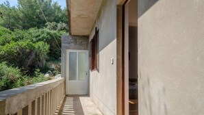 A narrow outdoor corridor with a concrete railing, a door, and a wall with a window. - Seafront Apartments Olivera-One Bedroom Apartment with Balcony and Sea View ( Ante ) (Vela Luka)