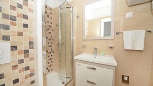 Ein Badezimmer mit Dusche, Waschbecken und Spiegel.