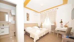 Ein Hotelzimmer mit Bett, Nachttisch, Stuhl und Schreibtisch mit Sitzgelegenheit.