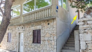 A stone building with a balcony, a door, and a staircase.