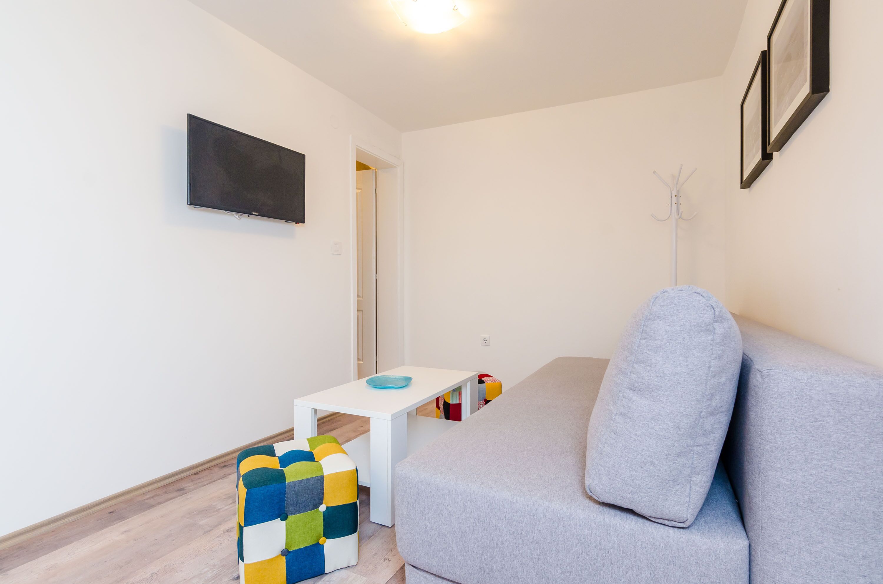 En moderne stue med en grå sofa, et hvidt sofabord og en farverig skammel.