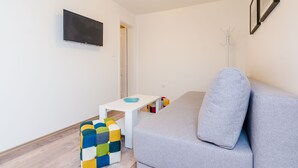 Una sala moderna con un sofá gris, una mesa de centro blanca y un otoman colorido.