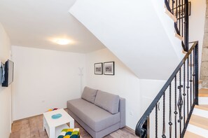 A modern living room with a grey sofa, a small white table, and a staircase with black railings. - Rooms Baza - Standard Double Room No.6 (Dubrovnik)