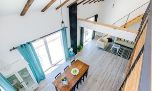 Amplia sala de estar con una mesa de comedor de madera, un sofá y una escalera.
