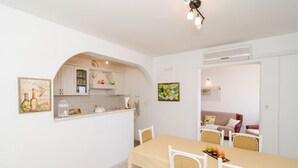 Un comedor con mesa y sillas, una cocina con armarios y encimera, y una sala de estar con sofá y un cuadro.