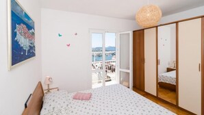 Un dormitorio con cama, mesita de noche, lámpara, armario y vistas al exterior.