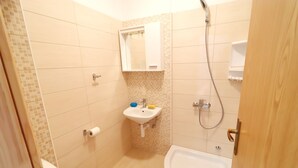 Et lille badeværelse med toilet, vask og badekar.