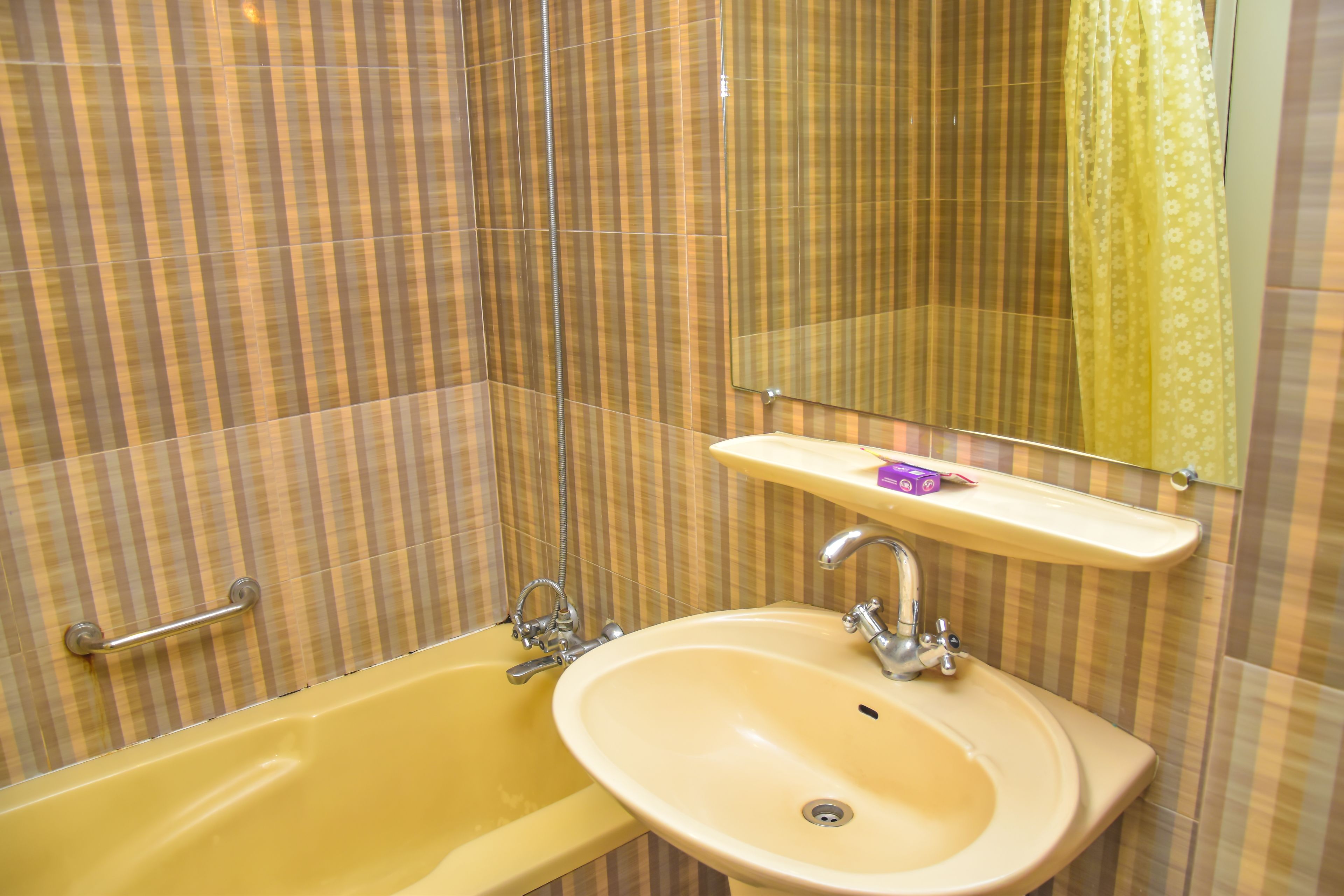 A bathroom with a yellow bathtub, a sink, and a mirror above the sink.