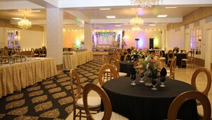 A banquet hall with round tables, chandeliers, and a patterned carpet. - Hotel Faran (Karachi)