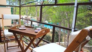 Un balcón con una mesa de madera, una silla y una mesita con una taza y un platillo.