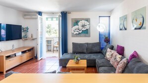 Een woonkamer met een bank, salontafel, televisie en kunstwerken aan de wanden.