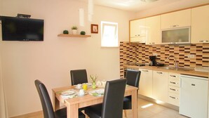 Eine moderne Küche mit Essbereich, inklusive einem Holztisch, schwarzen Stühlen, einem an der Wand montierten Fernseher und einer gefliesten Rückwand.