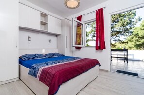 A bedroom with a bed, a window with red curtains, and a view of trees outside.