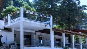 A two-story building with a stone facade, a balcony with railings, and a covered porch area.