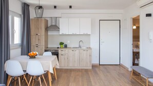 A modern kitchen with wooden cabinets, a built-in oven, and a dining area with a table and chairs.