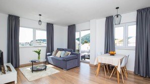 A modern living room with a sofa, a dining table, and a TV.