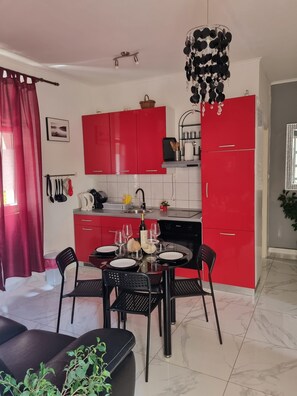 A modern kitchen with red cabinets, a dining table set for four, and a chandelier.