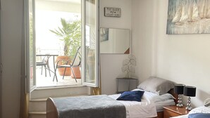 A hotel room with two beds, a balcony, a painting, and a sign on the wall. - Apartments Mavi - Two-Bedroom Apartment with Terrace and City View (Dubrovnik)