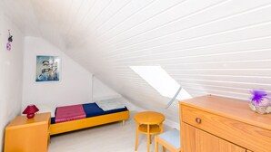 A small, well-lit attic bedroom with a slanted ceiling, a single bed, a small table, a chair, and a dresser. - Rooms Jozomare - Single Room with Shared Bathroom (Dubrovnik)