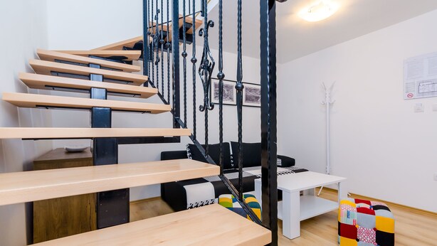 Una escalera moderna con escalones de madera y barandales de metal negro.