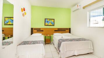 Una habitación de hotel con dos camas, una pared verde y una ventana.