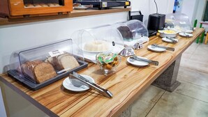 Ein reichhaltiges Buffet mit verschiedenen Speisen unter Abdeckungen, darunter Brot und Reis, sowie Besteck auf dem Tisch.