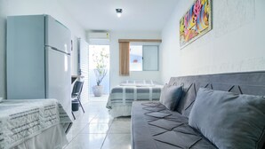 Ein kleines Hotelzimmer mit Bett, Sofa, Schreibtisch und Kühlschrank.