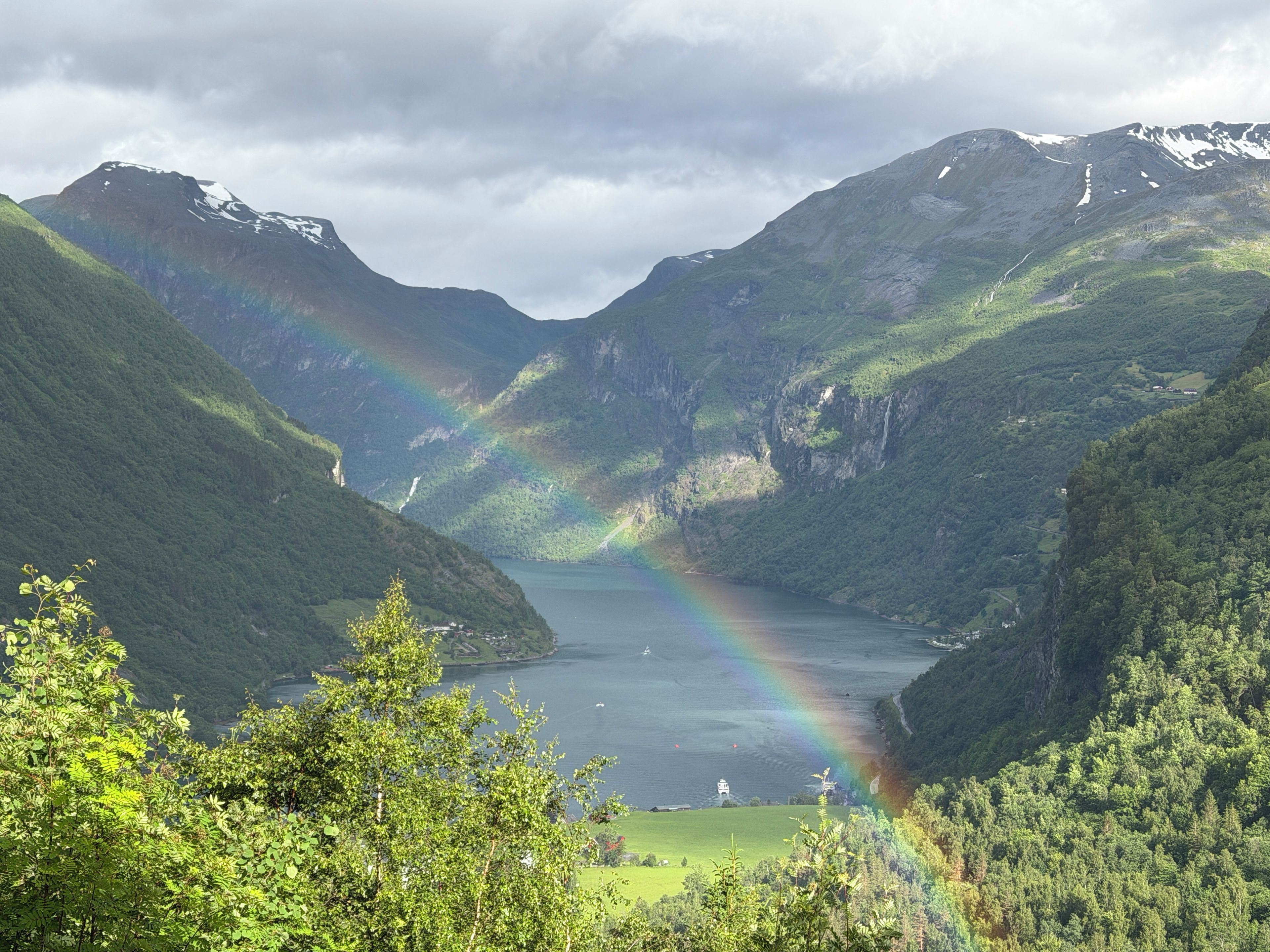 Een vallei met een meer, bergen en een regenboog.