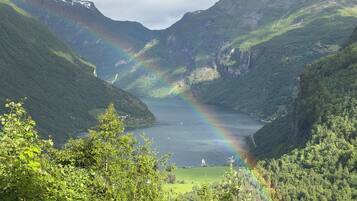Een vallei met een meer, bergen en een regenboog.