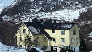 A two-story house with a sloped roof, a driveway, and a tractor parked in front. - Lunheim Accomodation (Stranda)